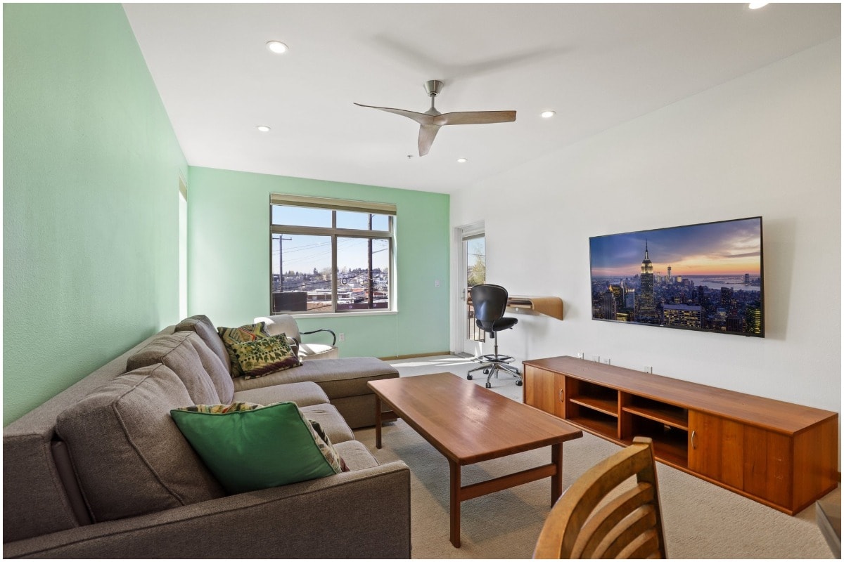 green lounge room with couch and tv and floating wood desk