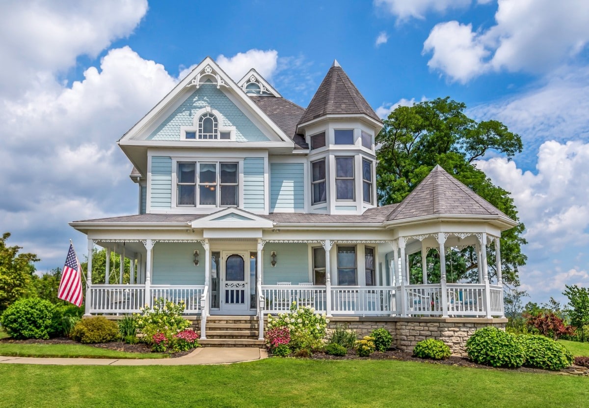 victorian farmhouse with blue exterior and manicured lawn