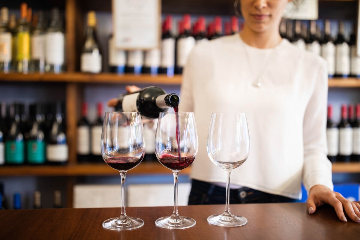 Bartender serving red wine in a winery